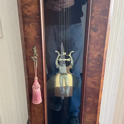Vintage grandfather clock featuring a burl wood veneer case, brass weights, and a lyre-shaped pendulum bob.