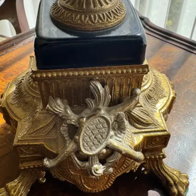 Ornate brass and black glass lamp base featuring claw feet and a decorative silver-tone metal crest.
