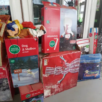 Assorted boxed outdoor Christmas decorations, including a Winter Wonder Lane dog and mailbox set, a pop-up snowman, and a light-up gift...