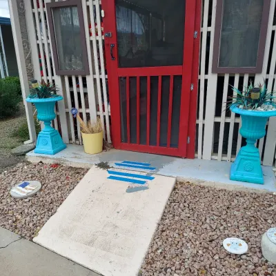 Pair of vintage cast iron urn planters painted bright turquoise, flanking a red screen door entryway.