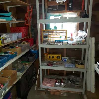 Five-tier gray plastic shelving unit filled with various workshop supplies, hardware organizers, and storage bins.