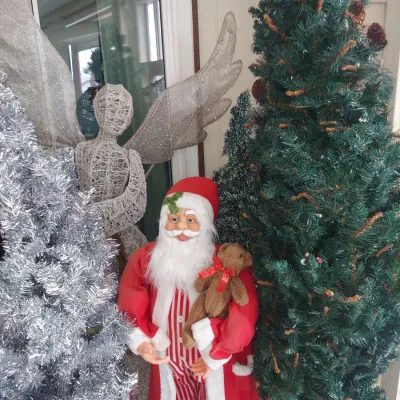 Assorted Christmas decorations, including a standing Santa Claus figure holding a teddy bear, a silver tinsel tree, a green artificial...