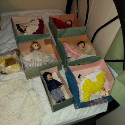 Collection of vintage Madame Alexander Storybook dolls in their original boxes, displayed alongside lace linens.