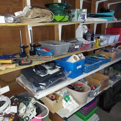 Assorted garage and workshop items, including extension cords, hand tools, storage bins, and hardware, organized on wooden shelving.