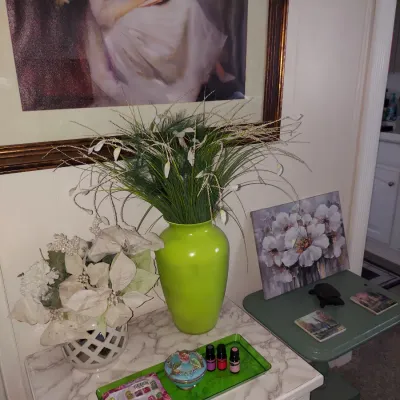 Assorted home decor items including a vibrant lime green ceramic vase with faux grass, a white lattice vase with faux poinsettias, and...