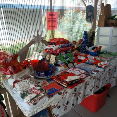 Assortment of Christmas-themed holiday decor, linens, and blankets displayed on a table at an outdoor estate sale.