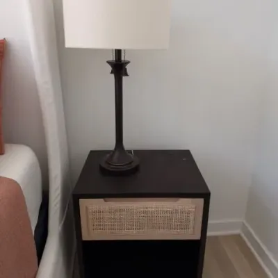 Black nightstand with cane drawer and table lamp