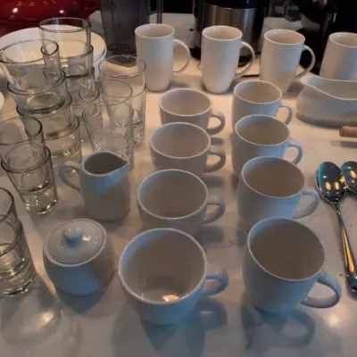 White coffee mugs, drinking glasses, creamer and sugar