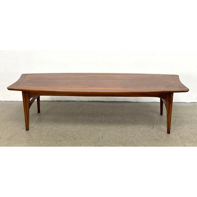 Mid Century Modern walnut surfboard coffee table featuring sculptural arched stretchers and tapered