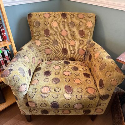 Contemporary upholstered armchair featuring a textured olive green fabric with a brown and beige circular pattern.