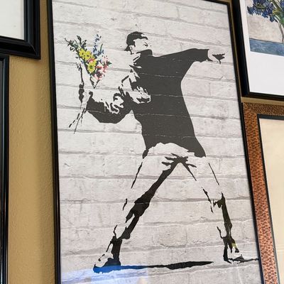Framed poster of Banksy's iconic "Flower Thrower" stencil art, depicting a protester throwing a bouquet of flowers against...