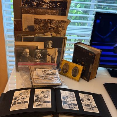 Collection of antique and vintage family photographs, including loose portraits, a small double-oval frame, and open photo albums showing...