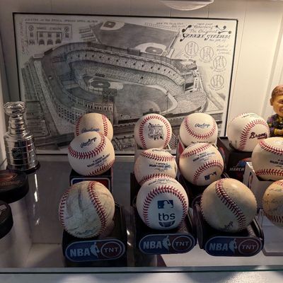 Collection of sports memorabilia, featuring several baseballs, including MLB and TBS branded balls, NHL pucks, a miniature Stanley Cup,...