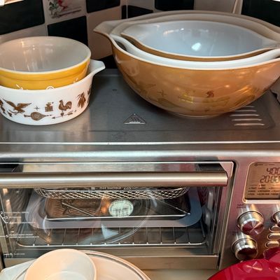 Stainless steel countertop toaster oven with digital display, shown with vintage Pyrex nesting bowls in the "Early American"...