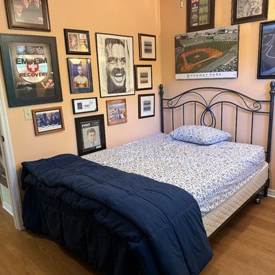 Black metal arch-style queen bed frame with mattress and box spring.