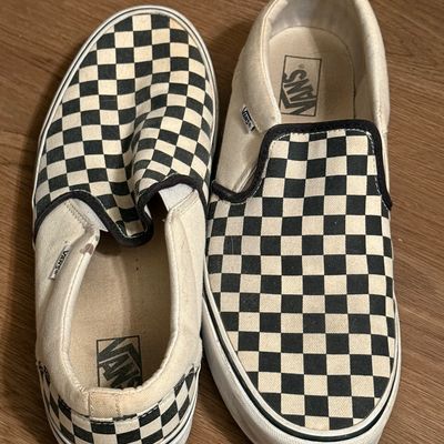 Pair of classic Vans slip-on sneakers featuring the iconic black and white checkerboard pattern, showing light wear.
