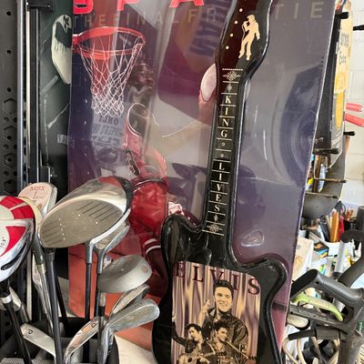 Novelty Elvis Presley guitar-shaped wall clock reading "The King Lives," displayed next to a Michael Jordan poster and a bag of...