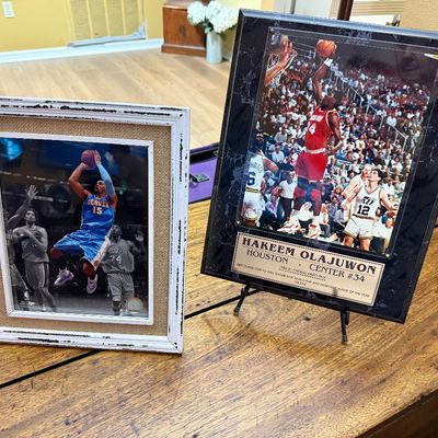 Two framed NBA basketball memorabilia items, featuring a Carmelo Anthony Denver Nuggets photo in a rustic white frame and a Hakeem...