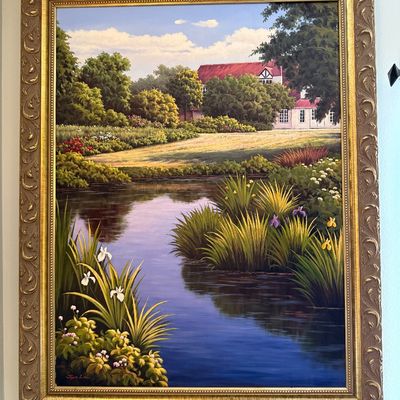 Large oil painting of a scenic landscape featuring a pond, lush gardens, and a Tudor-style house in the background, housed in an ornate...