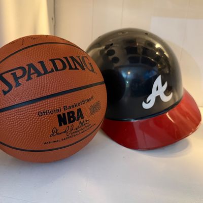 Miniature Spalding NBA basketball alongside an Atlanta Braves souvenir batting helmet.