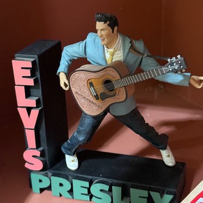 McFarlane Toys Elvis Presley action figure, depicting his 1956 performance style with guitar and name-branded display stand.