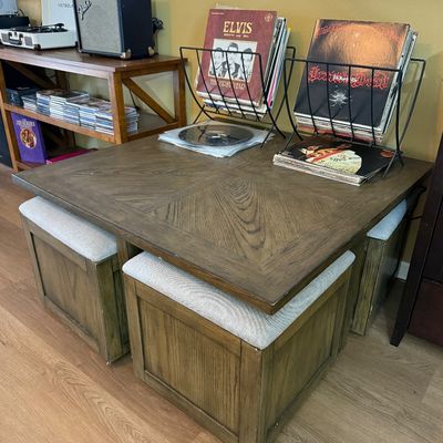 Contemporary square wooden coffee table with four matching tuck-under upholstered storage stools.