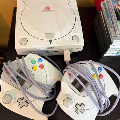 Sega Dreamcast video game console with two original controllers, showing some light surface wear, circa late 1990s.