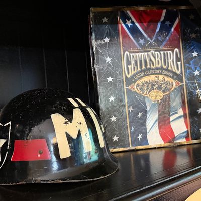 Vintage military police helmet liner with hand-painted "MP" lettering and insignia, displayed alongside a Gettysburg Limited...