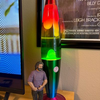 Retro rainbow-colored lava lamp with a metallic multi-color base and cap, shown next to a Jerry Garcia action figure.