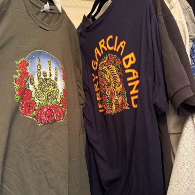Vintage Jerry Garcia Band and Grateful Dead graphic t-shirts hanging on a closet rack.
