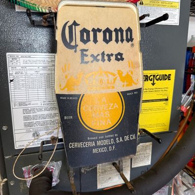 Vintage Corona Extra beer bottle-shaped wall sign, showing some age-related wear and discoloration.