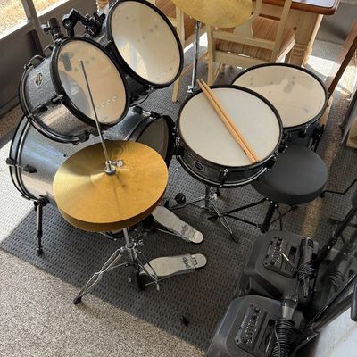 PDP five-piece drum kit with a silver sparkle finish, including cymbals, hardware, pedals, a drum throne, and two portable PA speakers...
