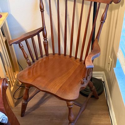 Vintage wooden Windsor-style armchair featuring a high spindle back, contoured seat, and turned legs.