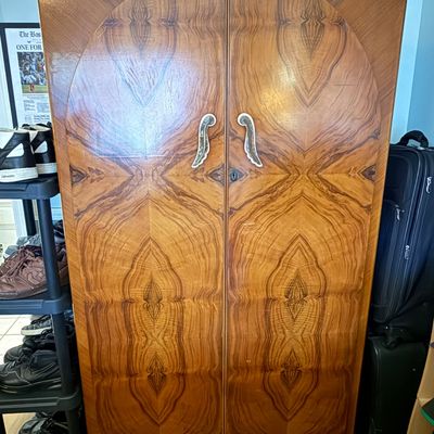 Art Deco style wooden armoire featuring book-matched veneer doors with an arched design and ornate metal handles.
