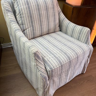 Upholstered armchair featuring a blue and white striped pattern, sloped arms, and a matching back cushion.
