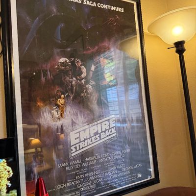 Framed theatrical release poster for "The Empire Strikes Back," featuring classic artwork of Luke Skywalker on a Tauntaun, Han...