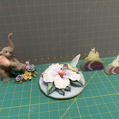 Four piece figurine set - elephant with flower. “Where’s my mom,”? Hummingbird on stained glass with hibiscus. Two cast castle, Hydro...