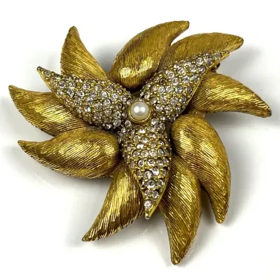 Vintage gold-tone textured metal floral brooch, featuring rhinestone-encrusted petals and a central faux pearl accent.