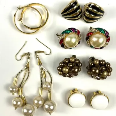 Assortment of vintage costume earrings, featuring gold-tone hoops, pearl dangles, and various clip-on styles with enamel, faux pearl, and...