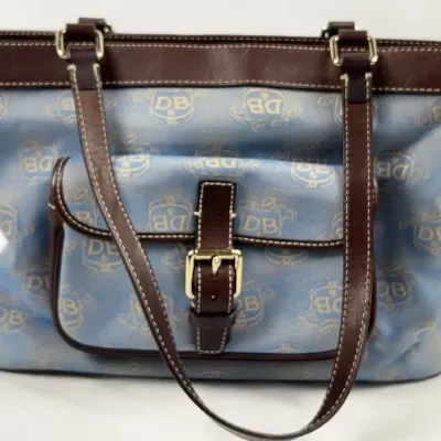 Dooney & Bourke signature monogram tote bag in light blue coated canvas with brown leather trim and handles.