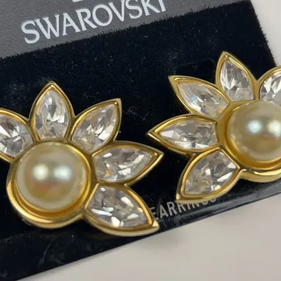 Vintage Swarovski gold-tone clip-on earrings featuring a central faux pearl surrounded by marquise-cut crystals in a fan design,...