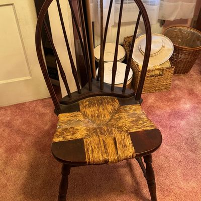Vintage Windsor-style wooden side chair featuring a hoop back with spindles and a woven rush seat showing some wear.