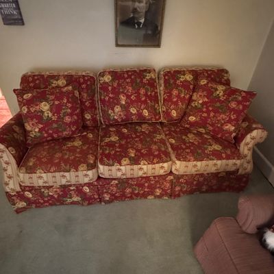 Broyhill Traditional three-cushion sofa featuring a red and cream floral upholstery with matching throw pillows and striped trim details.