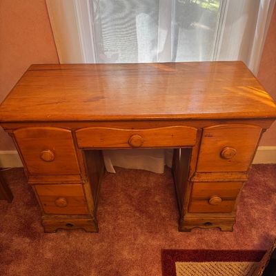 Vintage pine kneehole desk featuring five drawers with wooden knobs and a warm honey finish.