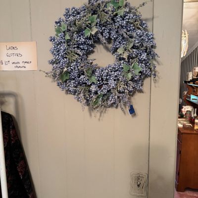 Decorative faux berry wreath in shades of blue and purple, accented with green leaves and frosted details.