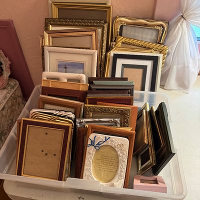 Large collection of assorted picture frames in various sizes, styles, and finishes, including wood, gold-toned, and silver-toned,...
