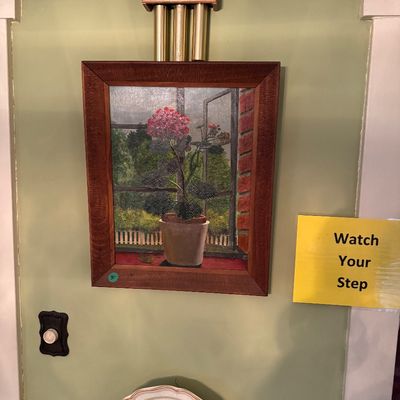 Framed oil painting depicting a potted pink geranium in a window, housed in a textured wood frame.