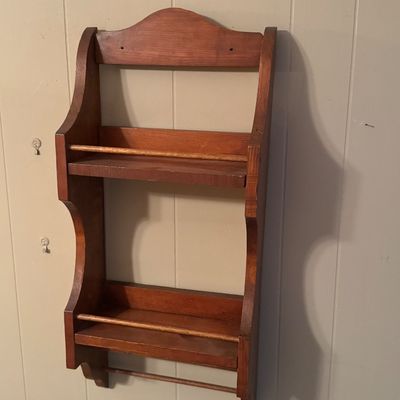 Vintage wooden wall-mounted spice rack or display shelf with two tiers, retaining bars, and a bottom dowel rod.
