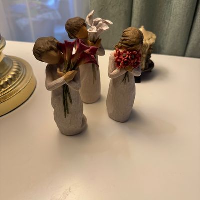 Three Willow Tree resin figurines by Susan Lordi, each depicting a faceless figure holding a different bouquet of flowers.