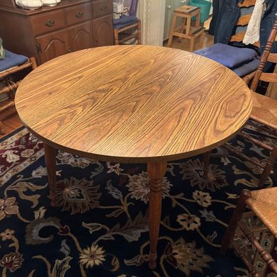 Round oak dining table with a laminate top and turned legs
